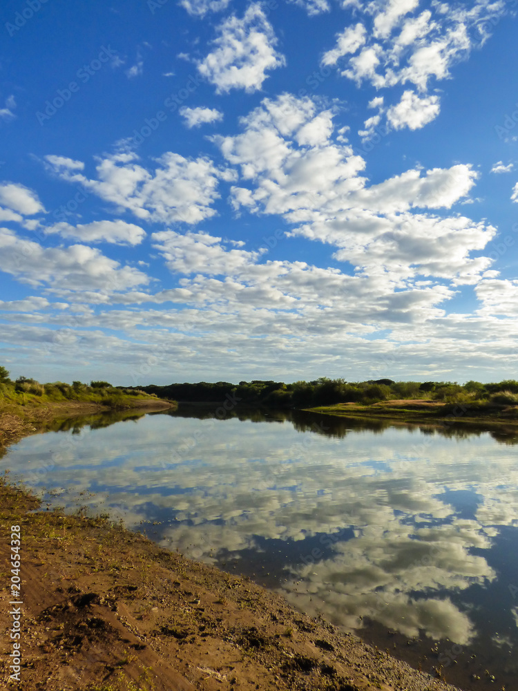 Fototapeta premium A view of the pampa biome, clouds reflecting on the Uruguay river - Uruguaiana, Brazil
