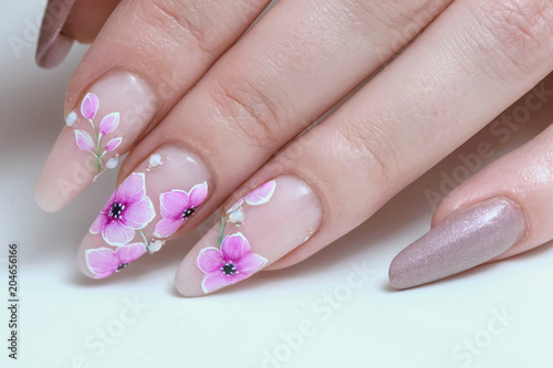 Finger nail treatment, hands with painted fingernails, female hand with floral art design nails