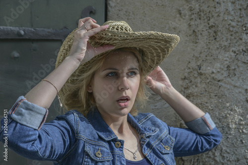 Foto girl with blond hair and blue eyes in a big straw hat is surprised with an open mouth
