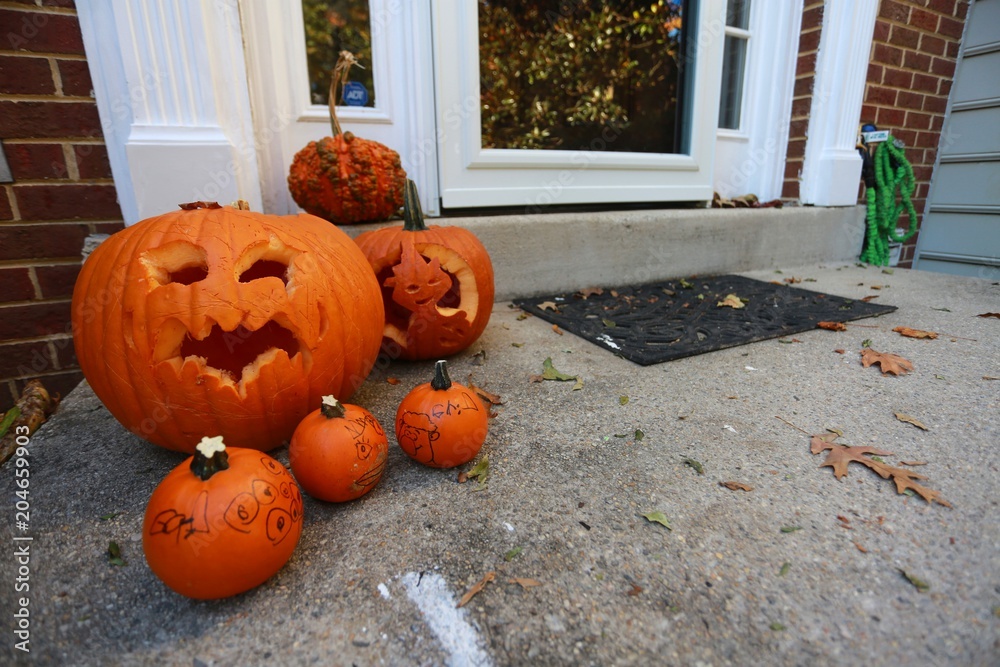 Obraz premium Large and Small Halloween Jack-o-Lantern Pumpkins on Doorstep of Town House in Burke, Virginia with Red Brick Walls
