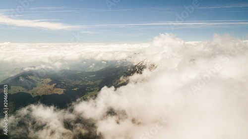 spring landscape with the mountain peaks covered with snow and clouds. aerial view by drone