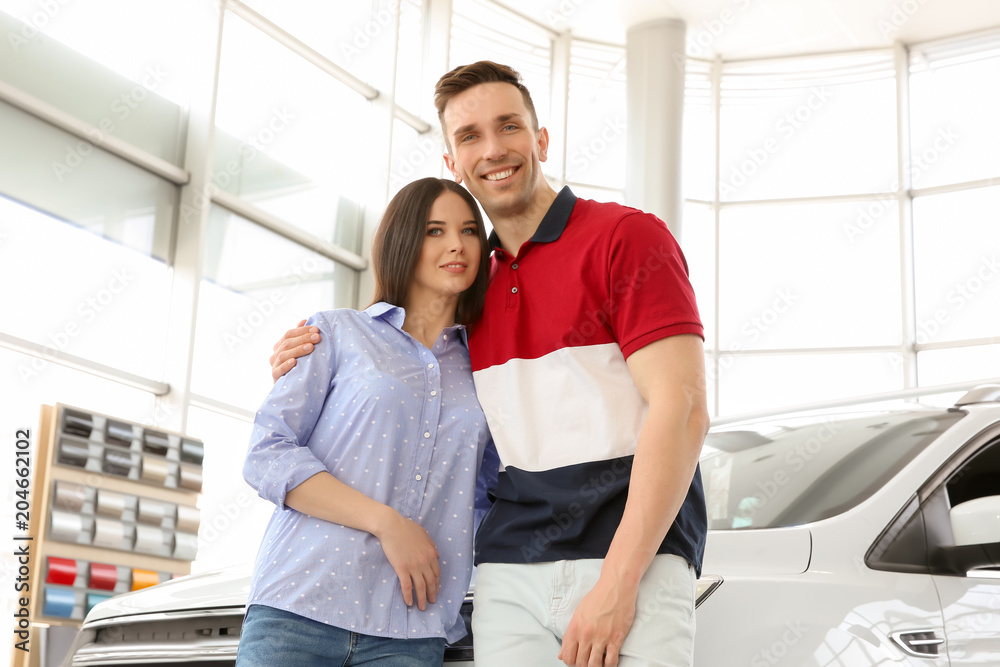 Young couple near auto in salon. Buying new car Young couple near auto in salon. Buying new car