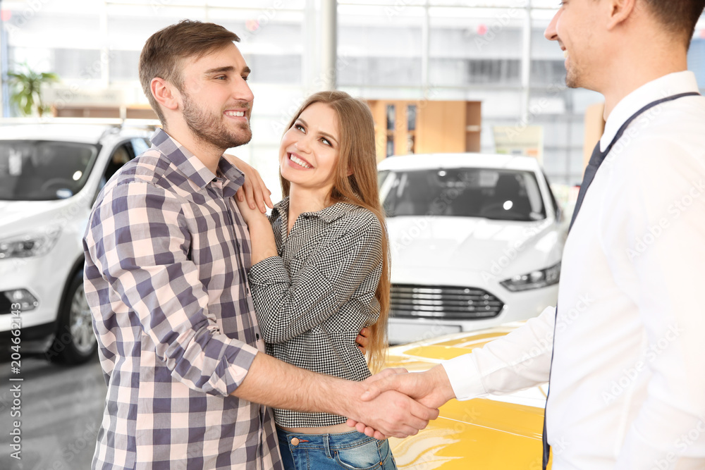 Young man shaking hands with salesman in car salon Young man shaking hands with salesman in car salon