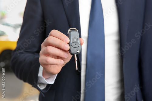 Businessman with key in dealership. Buying new car