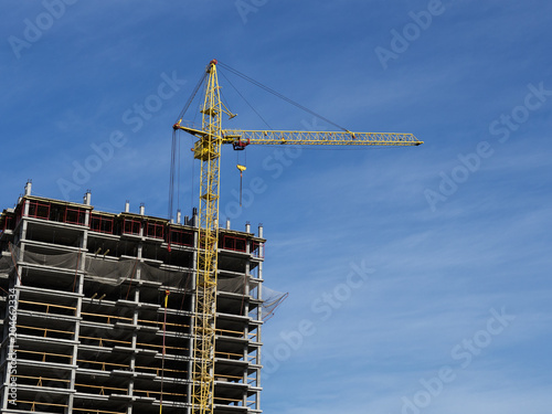 Construction crane on blue sky background. The construction of apartment buildings