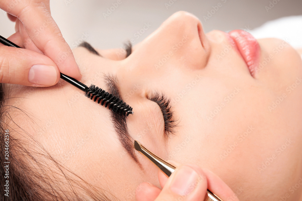 Young woman having professional eyebrow correction procedure in beauty salon, closeup