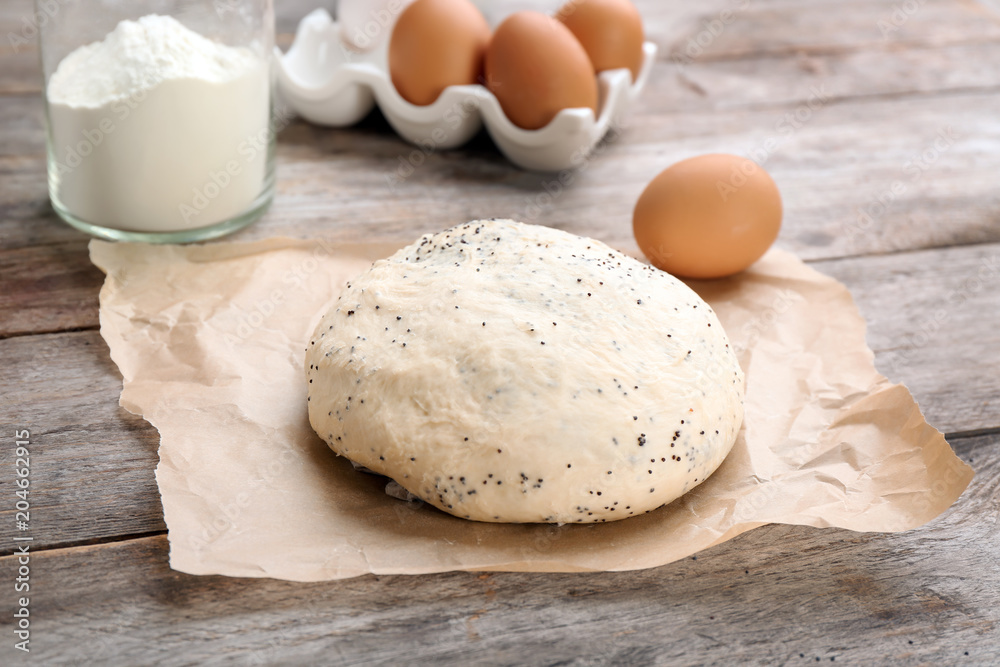 Raw dough with poppy seeds on wooden table Raw dough with poppy seeds on wooden table