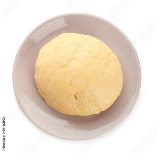 Plate with raw dough on white background, top view