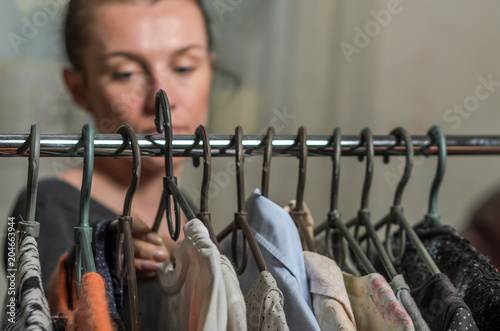 A young woman chooses clothes on hangers during shopping