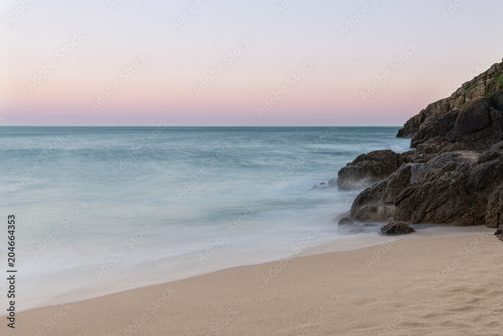 Stunning sunset landscape image of Porthcurno beach on South Cornwall coast in England