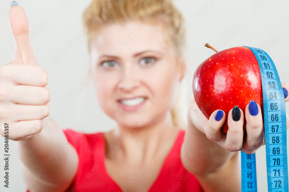 Happy woman holding apple and measuring tape Happy woman holding apple and measuring tape