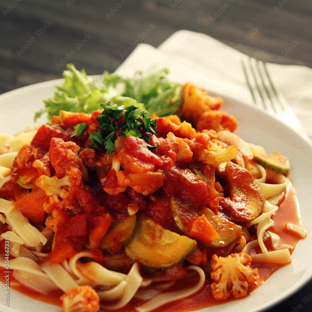 Ribbon pasta with Arrabiata sauce. Close up. Mediterranean dish. Tagliolini pasta with vegetables. Cauliflower, courgette and tomato stew. Italian cuisine. Vegan and vegetarian. Toned photo. Ribbon pasta with Arrabiata sauce. Close up. Mediterranean dish. Tagliolini pasta with vegetables. Cauliflower, courgette and tomato stew. Italian cuisine. Vegan and vegetarian. Toned photo.