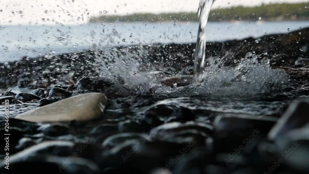 Stream of water pours on the stones, pebbles on the sea coast, scattering into lot of splashes and drops, Slow motion, Close up. Stream of water pours on the stones, pebbles on the sea coast, scattering into lot of splashes and drops, Slow motion, Close up.
