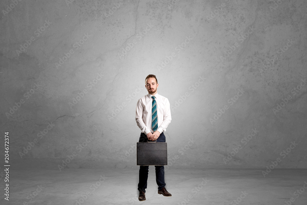 Alone handsome businessman standing in a dark empty room Alone handsome businessman standing in a dark empty room