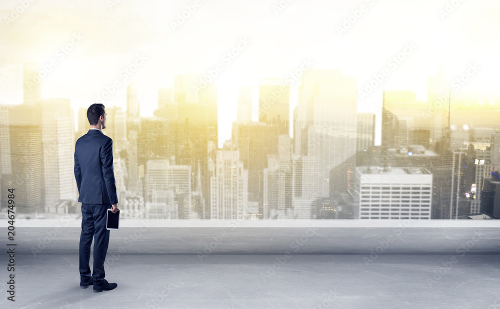 Businessman standing with his back on a roof with objects in his hand
