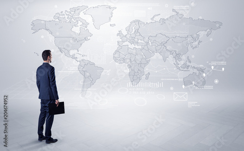 Fotografie Businessman standing with his back and looking at a worldwide map with objects i