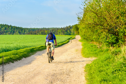 A cyclist riding a dusty road at sunset. Cycling on holiday in the Czech Republic. 