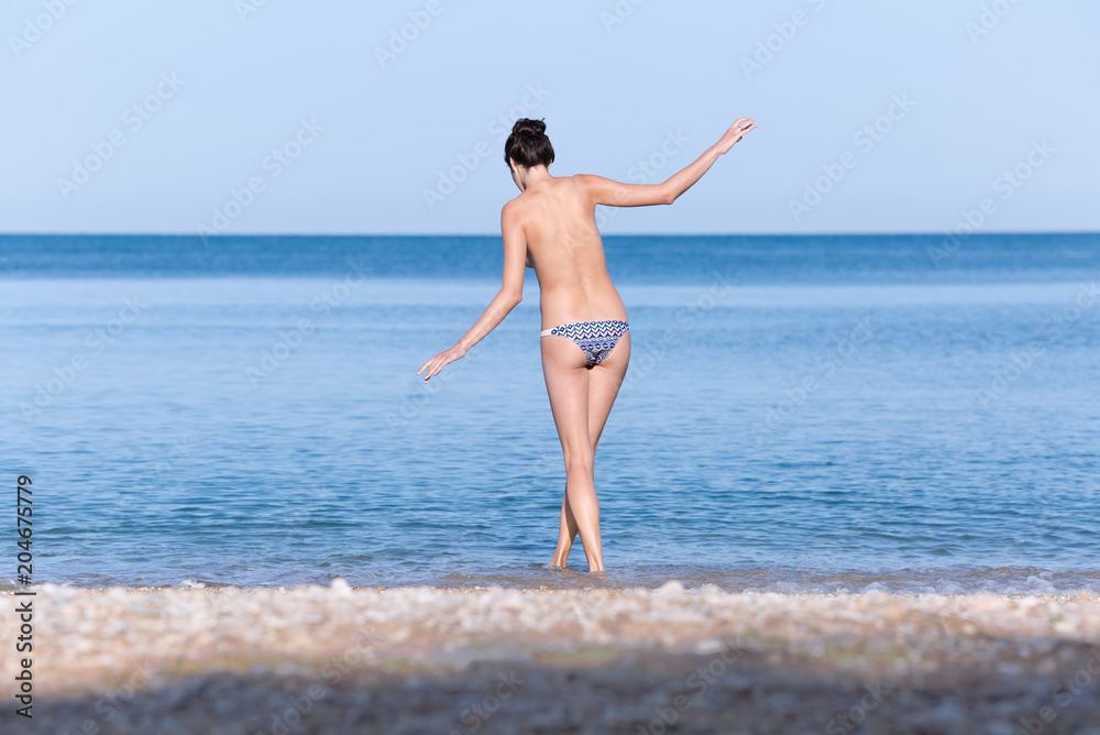 Young woman in bikini bottom entering in sea Young woman in bikini bottom entering in sea