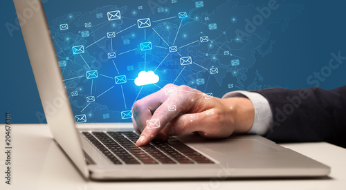 Businessman hand sending a bunch of messages on laptop with cloud computing concept 