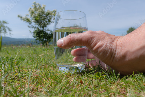 Glas mit Wasser in der Hand halten bei warmen Temperaturen