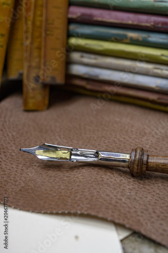 A vintage pen sitting on a piece of brown leather. Room for text! 