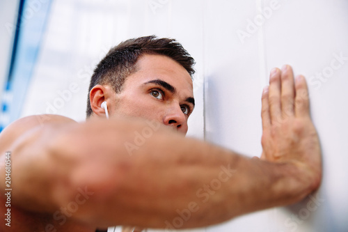 Close-up view of young sportsman doing push ups, listening to music in headset during training outdoors. © Maksym Azovtsev