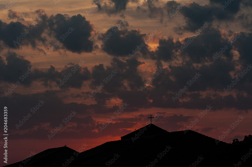 Silhouette of rooftops in the sunset. Red-orange sky.