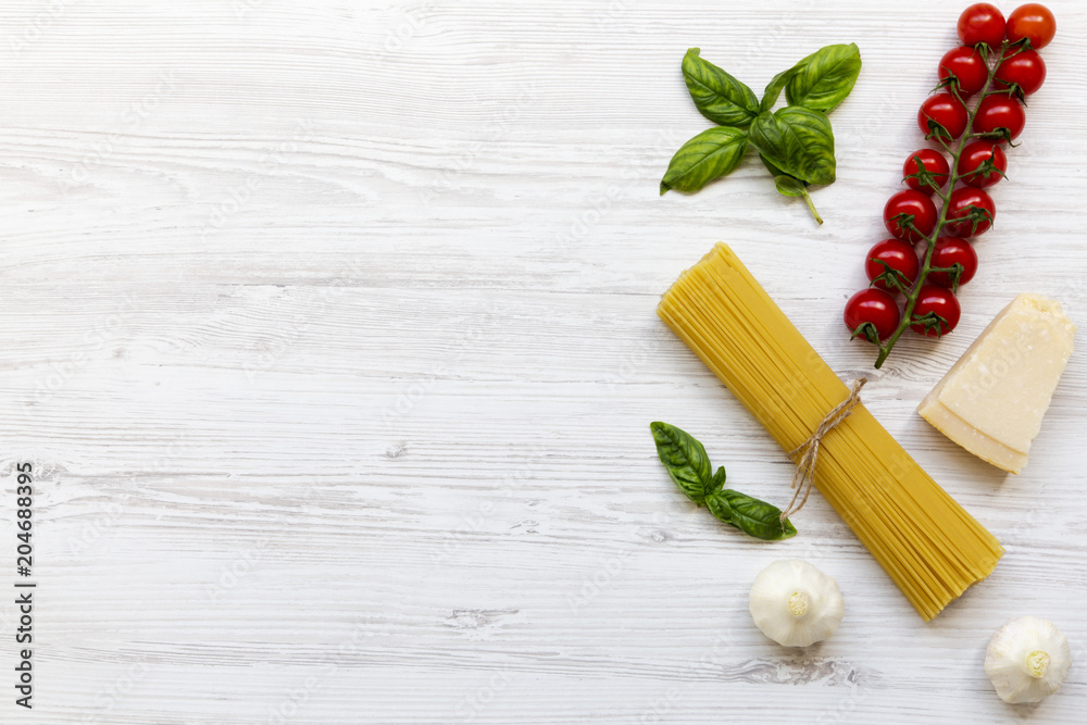 Pasta ingredients: spaghetti, cheese parmesan, garlic and tomatoes with basil on white wooden background, top view. Copy space. Pasta ingredients: spaghetti, cheese parmesan, garlic and tomatoes with basil on white wooden background, top view. Copy space.
