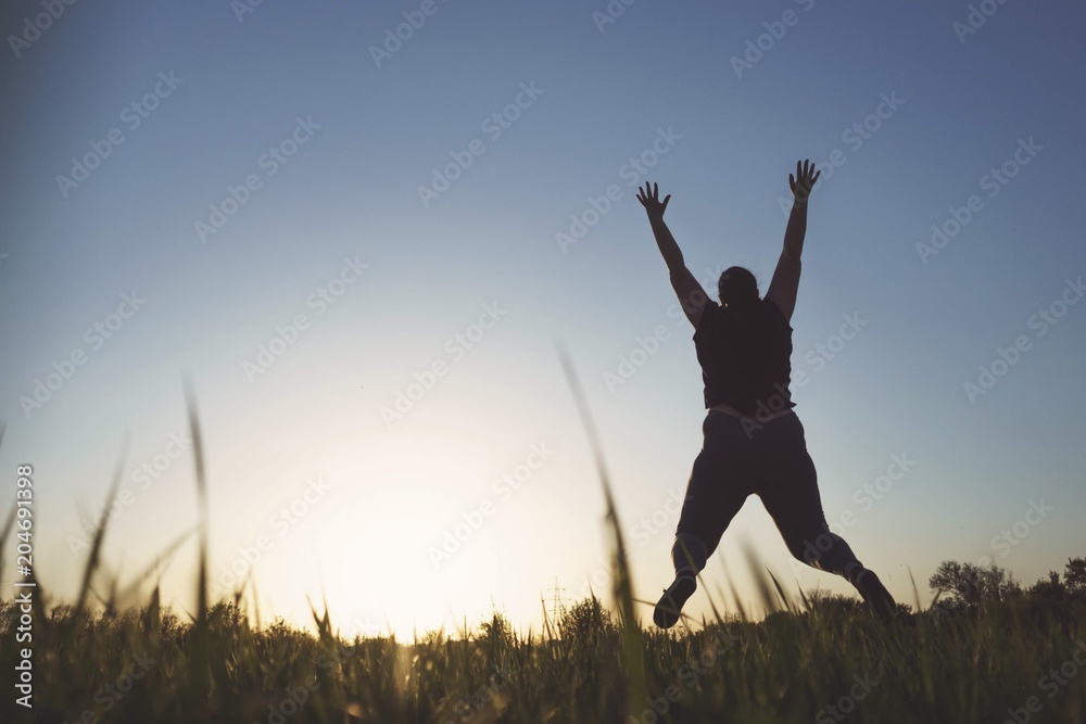 Body positive, high self esteem, confidence, freedom, happiness, inspiration, obesity. Overweight woman jumping high at sunset sky background Body positive, high self esteem, confidence, freedom, happiness, inspiration, obesity. Overweight woman jumping high at sunset sky background