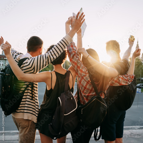 Traveling, sightseeing, group travel, city tour, student exchange program, vacation, holiday, togetherness and friendship. People with backpacks rising hands, joy and positivity