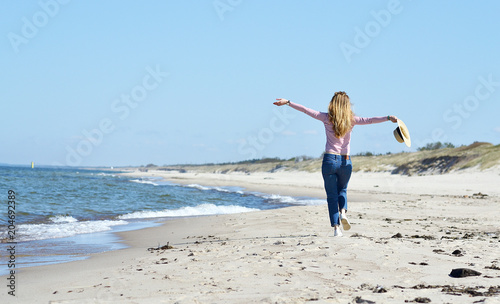 Young beautiful woman in a hat walks on the sea, sunny day, freedom concept 