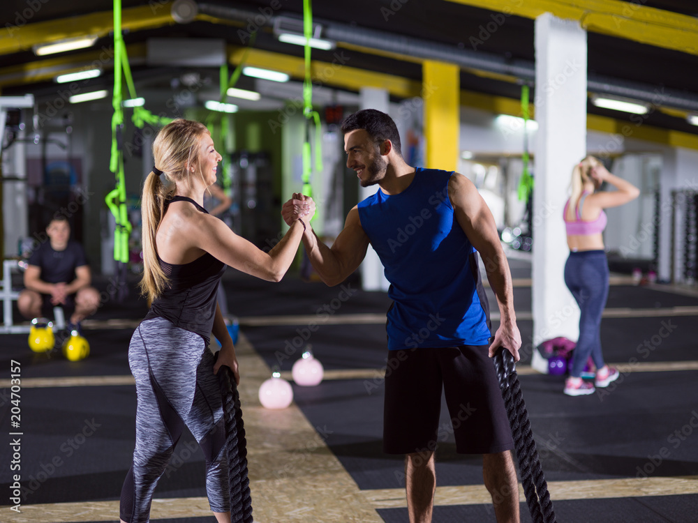 Obraz premium sports couple doing battle ropes crossfitness exercise