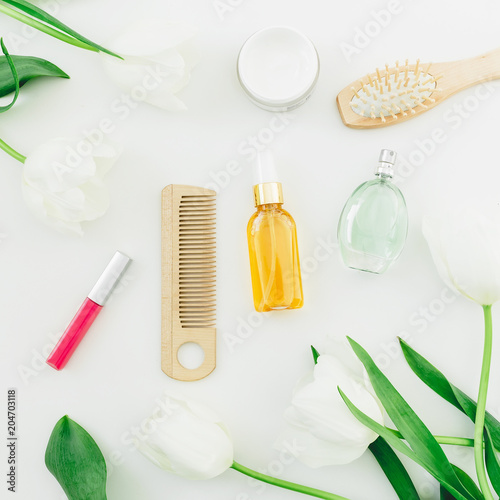 Cosmetic, perfume, combs and tulips flowers on white background. Beauty composition. Flat lay, top view
