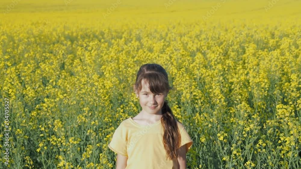 Child in the field. A little girl is spinning in a field of yellow flowers.Daughter of a farmer in a rapeseed field.