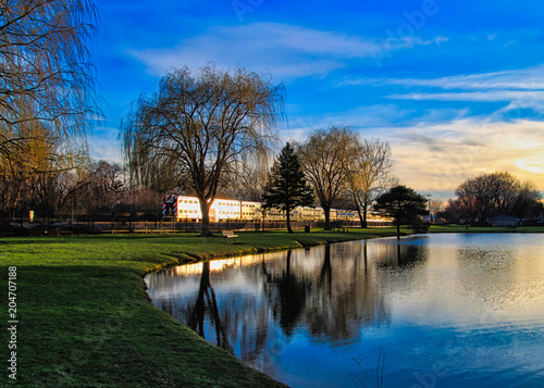 Wallpaper Mural Metra train travels through sunset and trees near midwestern park, reflected onto pond water. Torontodigital.ca