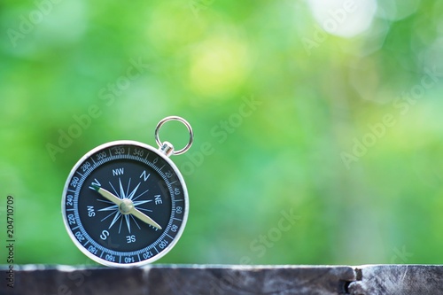 Compass with blur green background, journey planning concept