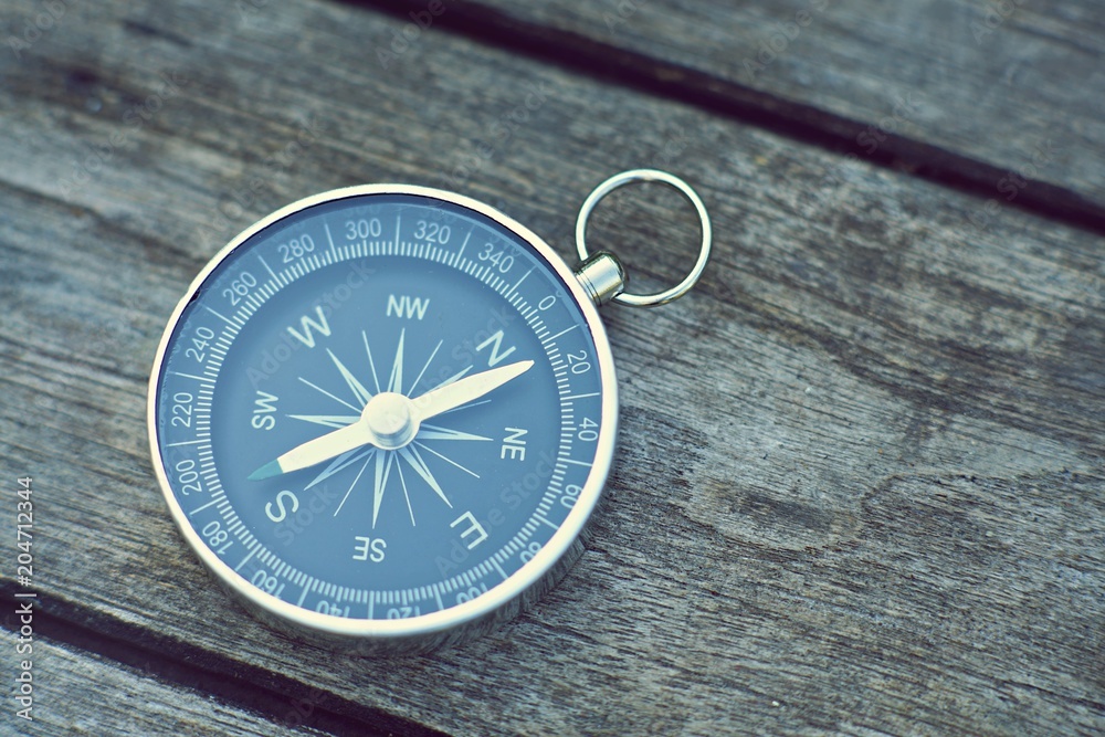 Compass on old wooden table background, journey concept, vintage tone