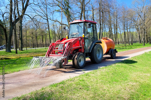 watering tractor on the road in the spring Park