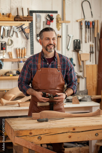 Joiner Makes Cabriole Leg for Vintage Table. Carpenter works with a planer in a workshop