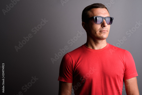 Man wearing red shirt and sunglasses against gray background