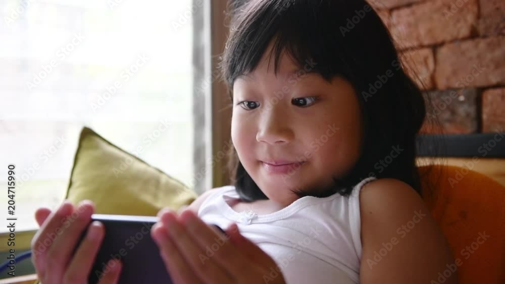 Happy little girl playing and seeing a mobile phone Happy little girl playing and seeing a mobile phone