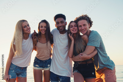 Group of happy friends having fun at ocean beach