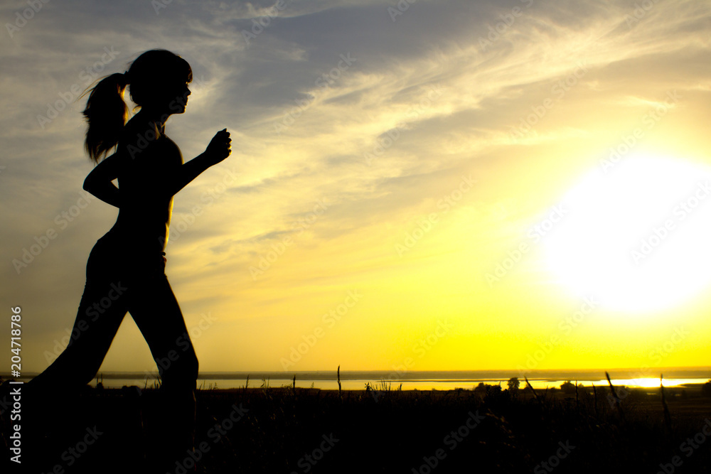 silhouette of a woman jogging on nature at sunset, sports female profile, concept of sport, leisure and healthcare