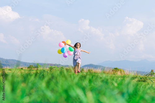 small girl holding air balloons and playing in park at summer