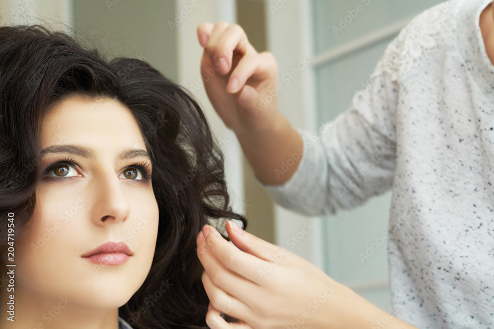 Fototapeta premium Closeup view of the hand and comb of a hairstylist combing a new hairstyle on a customer head in hair salon.