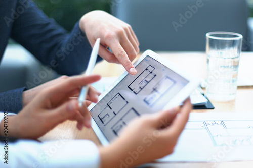 Real-estate agent showing house plans on electronic tablet.