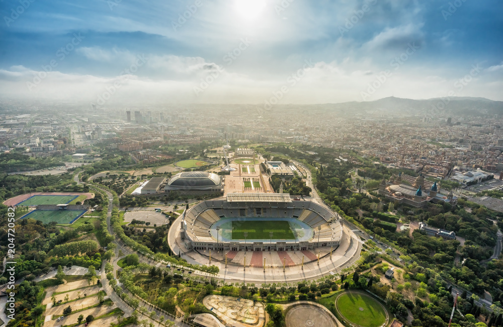Barcelona aerial panorama, Anella Olimpica sport complex on the hill with city skyline , Spain. Sunbeam light