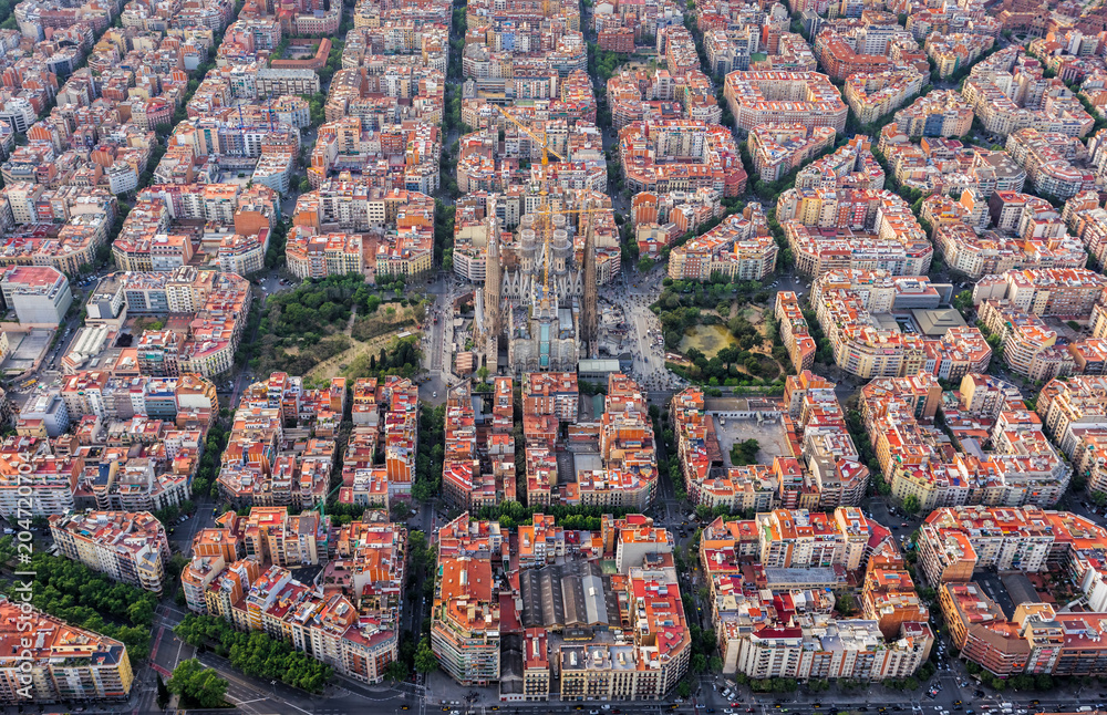 Fototapeta premium Widok z lotu ptaka na dzielnicę mieszkaniową Barcelona Eixample i Sagrada Familia wewnątrz typowych placów miejskich, Hiszpania. Miękkie światło późnego popołudnia