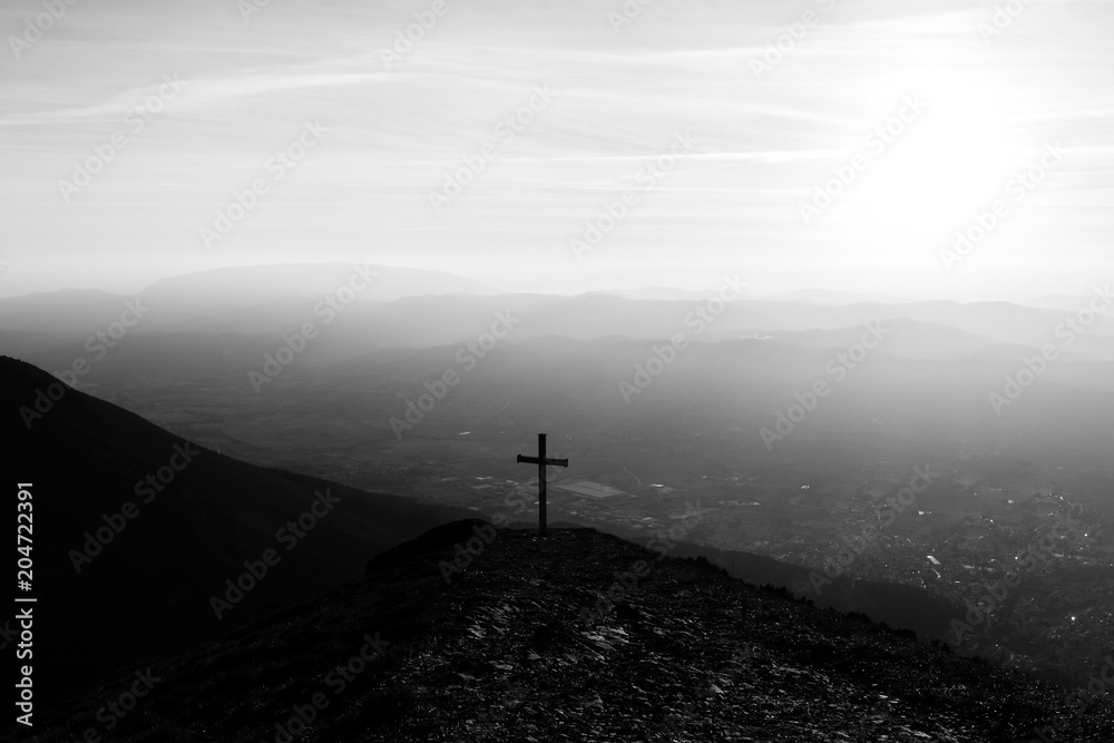 Obraz premium Cross on top of Mt. Serrasanta (Umbria, Italy), with sun low on the horizon