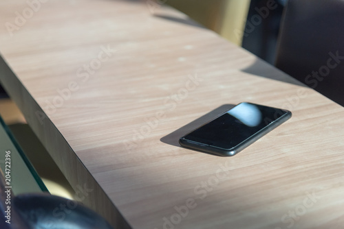 smart phone place on wooden table in coffee shop, Concept : Forget / lost, Selective focus